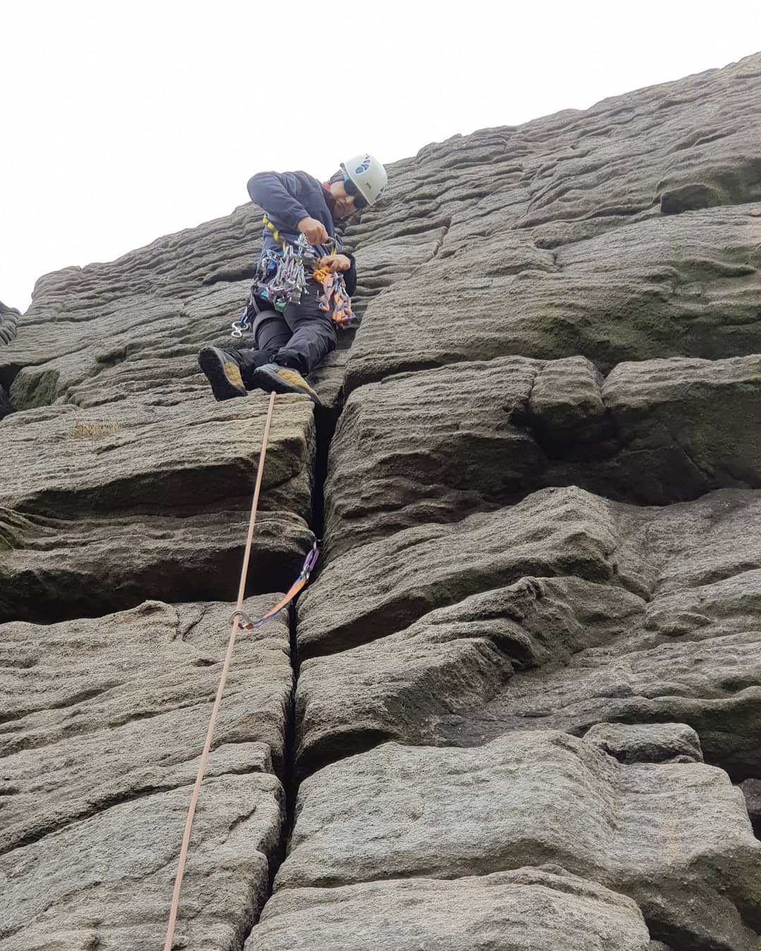 Climber leading a traditional climbing route in the Peak District using natural protection.