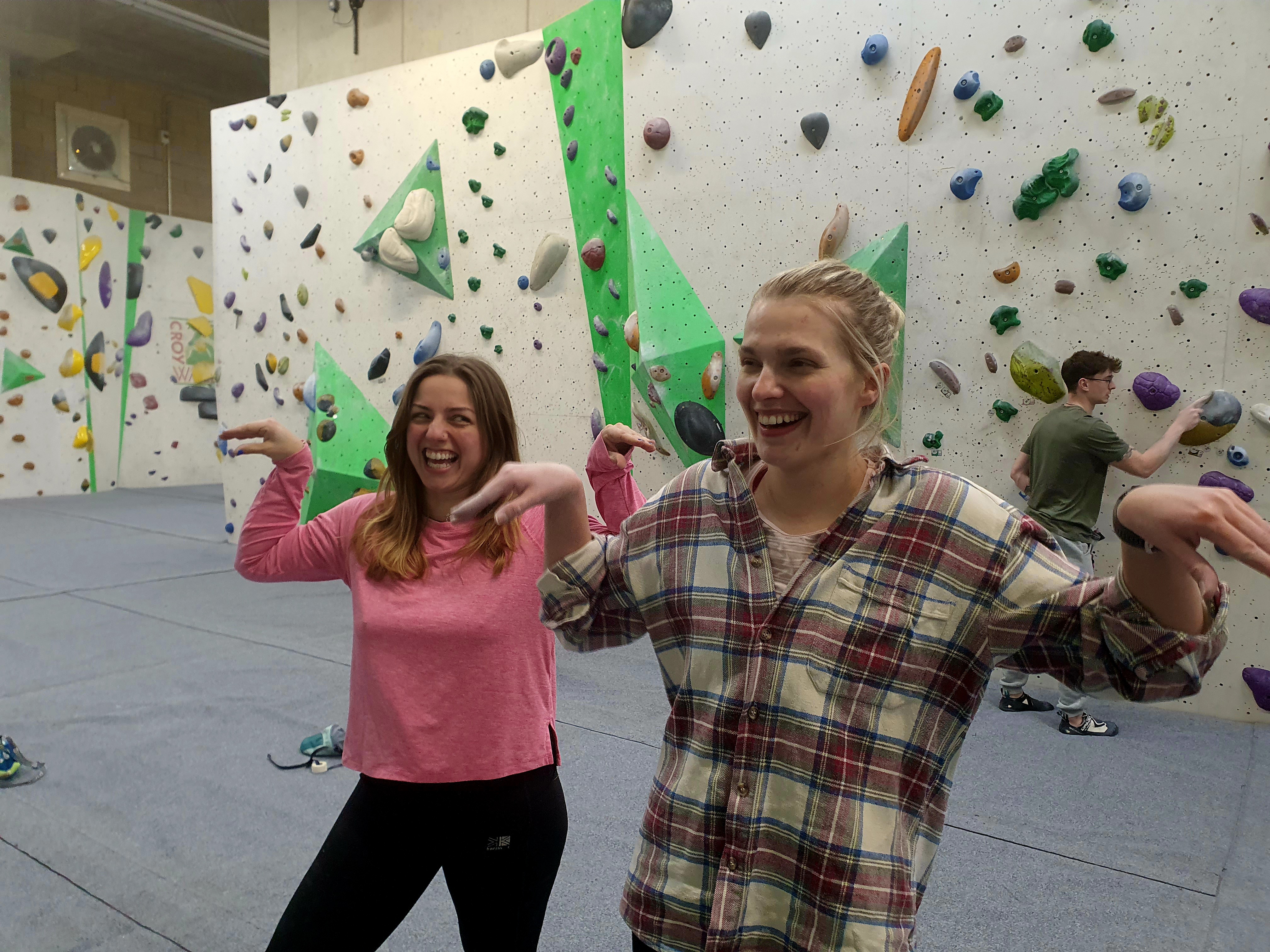 Adults learning beginner bouldering techniques at an indoor climbing centre.
