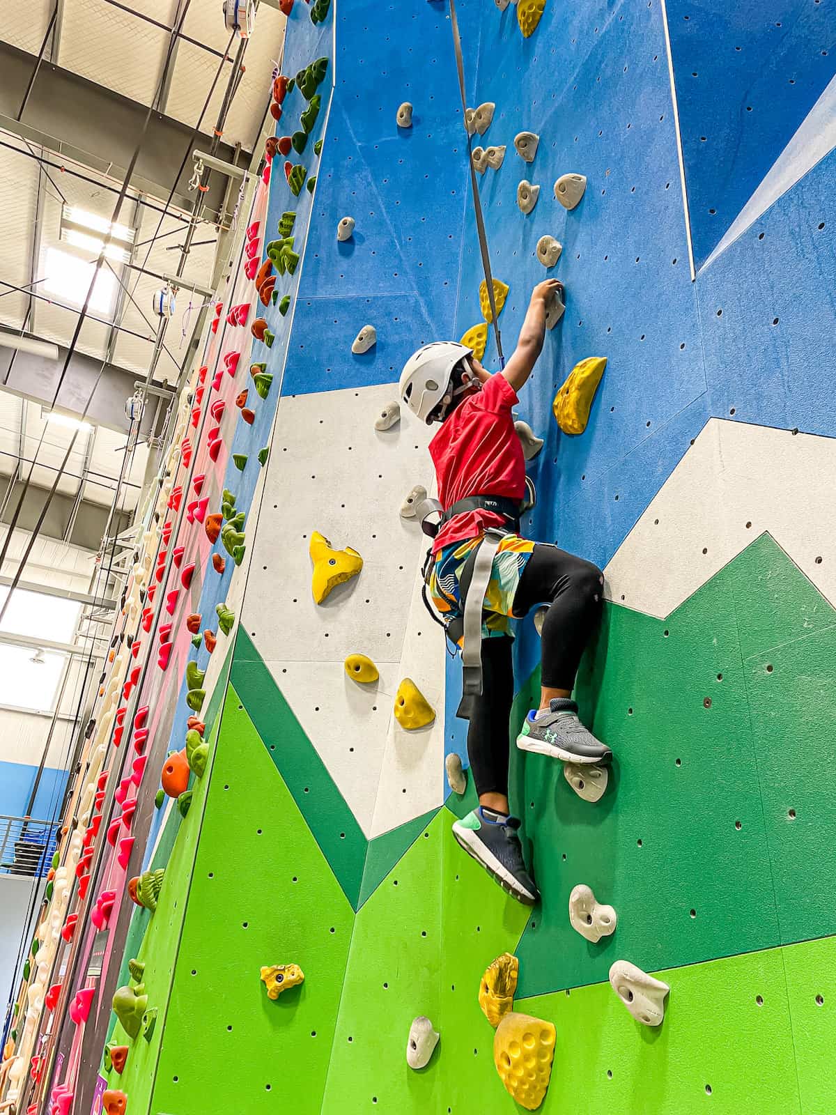 Child enjoying a private indoor climbing session with an instructor in a supportive environment.