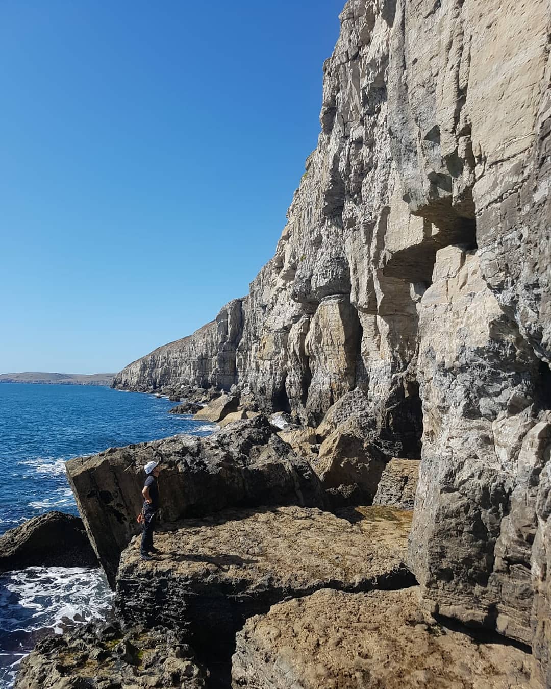 Lead climber ascending a limestone sport climbing route on the cliffs of Portland, Dorset.